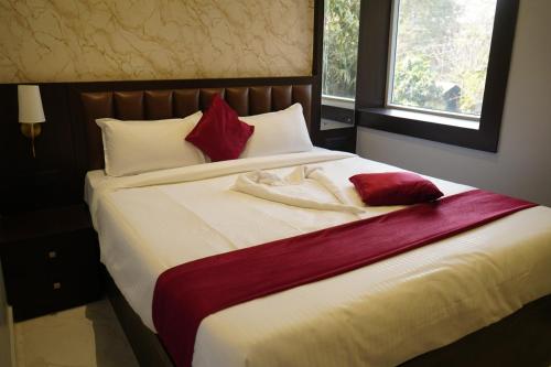 a bedroom with a large bed with red and white pillows at Sova Premium in Jagatsinghapur