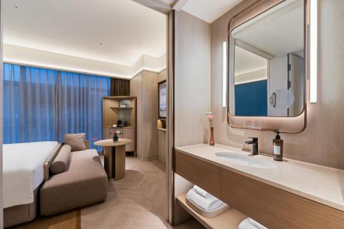 a bathroom with a bed and a sink and a mirror at Orange Crystal Hotel Yantai Binhai Square in Yantai