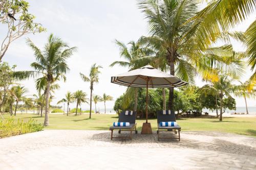 two chairs and an umbrella on a beach at Anantaya Resort and Spa Passikudah in Pasikuda