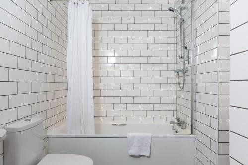 uma casa de banho branca com uma banheira e um WC em The Brighton Hotel em Brighton & Hove