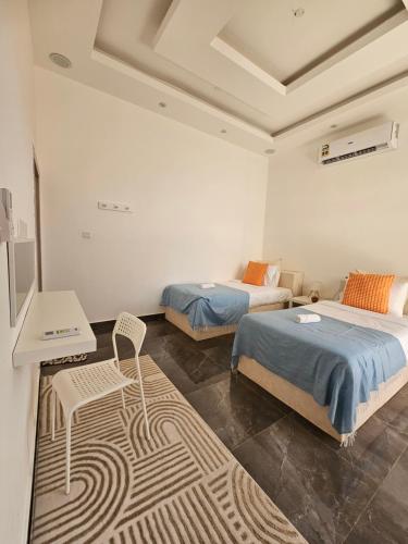 a bedroom with two beds and a table and a chair at TiDise Villas & Chalets إستراحة وشاليه تايدايس in Bimmah