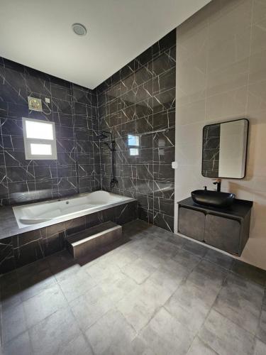 a bathroom with a tub and a tv on the wall at TiDise Villas & Chalets إستراحة وشاليه تايدايس in Bimmah