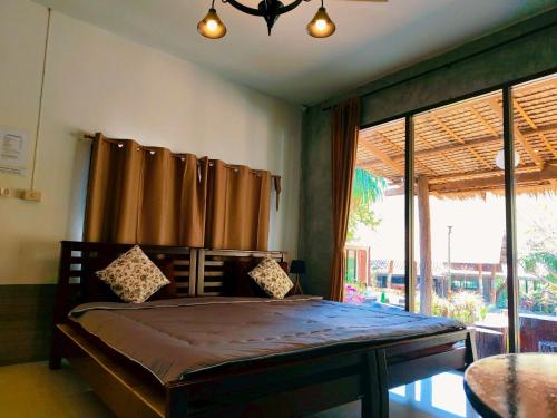 a bedroom with a bed and a large window at Phakphing Erawan Homestay - พักพิง เอราวัณ โฮมสเตย์ in Tha Kradan