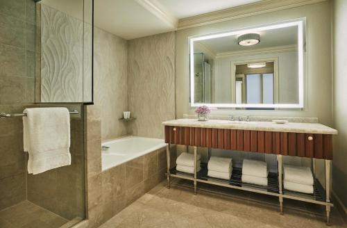 y baño con lavabo, bañera y espejo. en Four Seasons Washington DC, en Washington