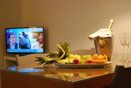 a plate of fruit on a table with a drink at Ceccarini Suite in Riccione