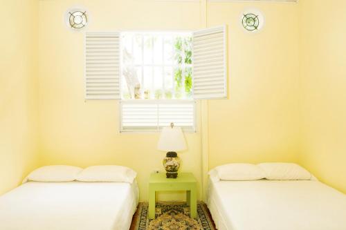 two beds in a room with a window and a table at Casamarilla in Mariquita