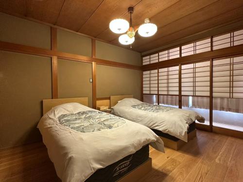 two beds in a room with two windows at Otsu Guesthouse Seiseki - Vacation STAY 90442v in Otsu