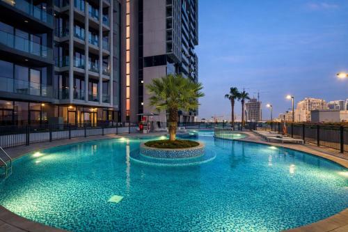 a large pool with a palm tree in front of buildings at Resort lifestyle, Fantastic Views, Bright & Brand new in Dubai