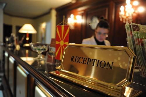 a woman standing behind a bar with a reputation sign at Millenium Palace in Ohrid
