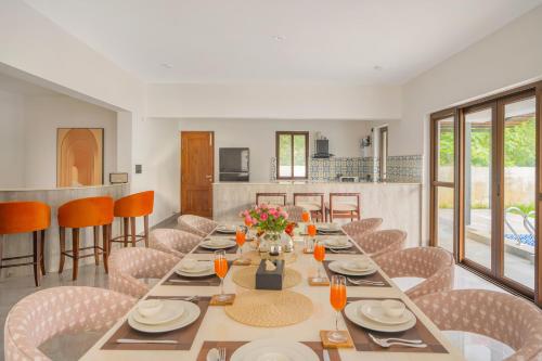 a dining room with a long table and chairs at ELIVAAS Signature Casa Verdea 4-BHK Villa With Private Pool & Lift Near Popular Restaurants in Siolim