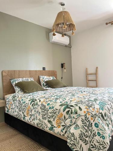 a bedroom with a bed with a comforter on it at Le Ravintsara in Saint-André