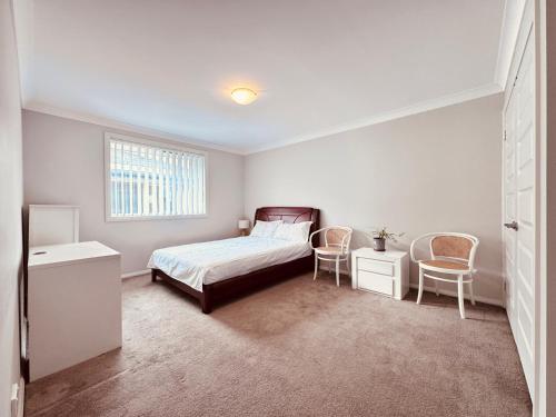 a bedroom with a bed and two chairs at A Zen Tea Sanctuary in Australia in Schofields
