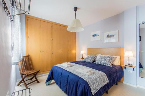 1 dormitorio con 1 cama azul y armario de madera en Apartamento PUERTA-CALETA by Cadiz4Rentals, en Cádiz
