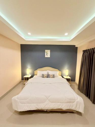 ein Schlafzimmer mit einem großen weißen Bett und zwei Tischen in der Unterkunft THAM Ranong in Ranong
