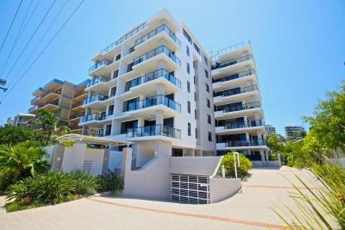a large white apartment building on the beach at Kings Row Apartments in Caloundra