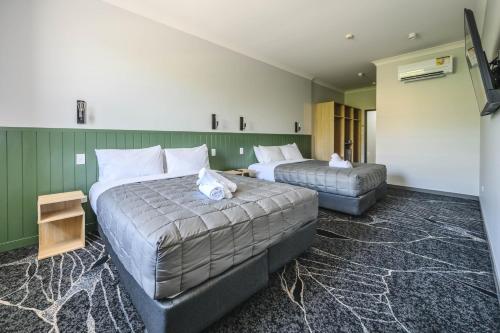 a hotel room with two beds and a television at Belmore Hotel Maitland in Maitland