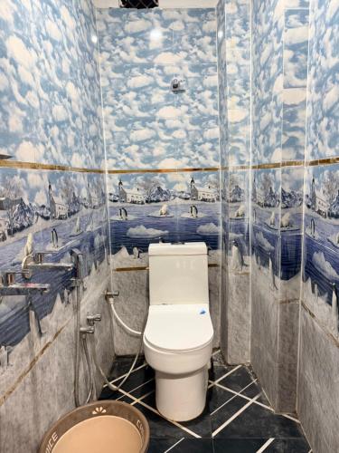 a bathroom with a toilet and a mural of clouds at Guru Amrit Residency & Guru Kripa Guest house in Ayodhya