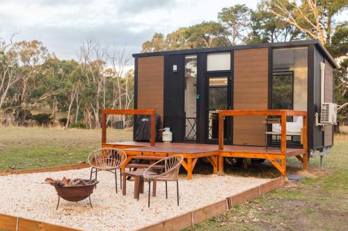 a tiny house with a table and chairs in a field at Boston's Retreat by Tiny Away in Inman Valley