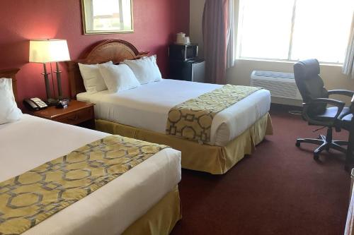 a hotel room with two beds and a chair at Baymont Inn & Suites by Wyndham Holbrook in Holbrook