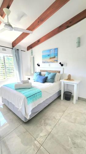a white bedroom with a large bed and a table at Chakas Rock Chalet 39 in Ballito
