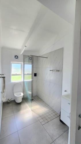 a white bathroom with a toilet and a shower at Chakas Rock Chalet 39 in Ballito