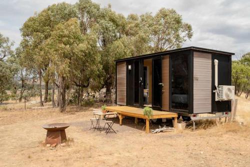 a tiny house with a table and a bench at Hill View at Euroa by Tiny Away in Euroa