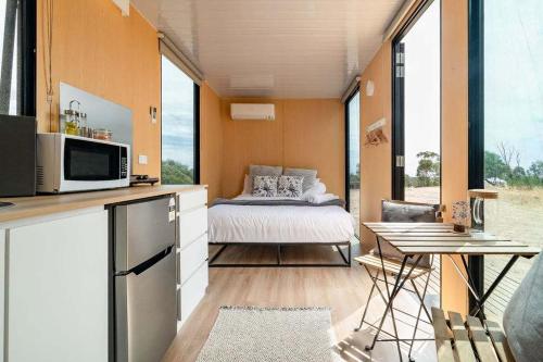 a bedroom with a bed in a room with large windows at Hill View at Euroa by Tiny Away in Euroa