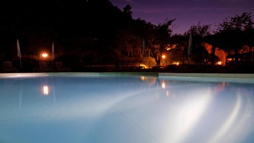 a large swimming pool lit up at night at Logis Hôtel Restaurant Le Domaine de l'Eau Vive in Largentière