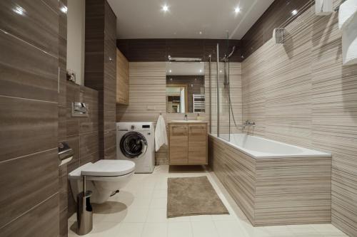 łazienka z toaletą, wanną i pralką w obiekcie Granus apartments w Druskienikach