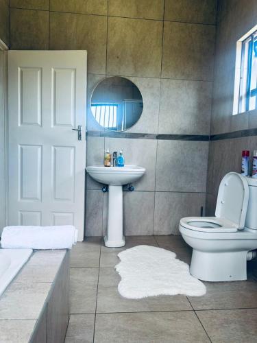 a bathroom with a sink and a toilet and a mirror at Elegant guest house in Matsapha