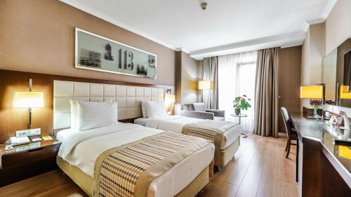 a hotel room with two beds and a desk at Kent Hotel Beyazıt in Istanbul
