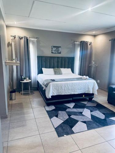 a bedroom with a large bed and a rug at Elegant guest house in Matsapha