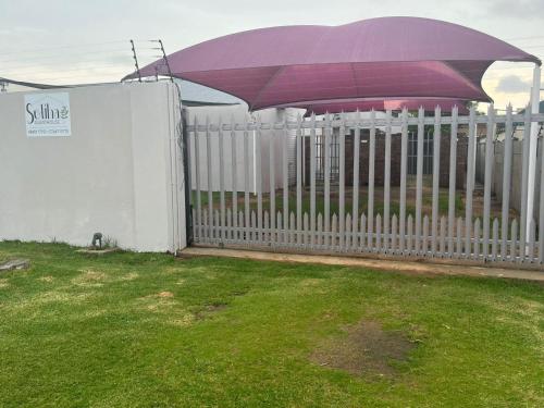 a white fence with an umbrella on top of it at Soliha Guesthouse in Trichardt