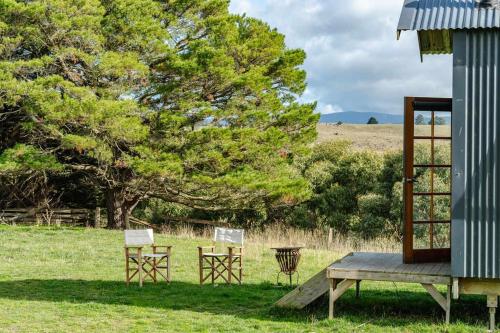 two chairs and a table in a field with a tree at Deep Creek Sunset by Tiny Away in Romsey