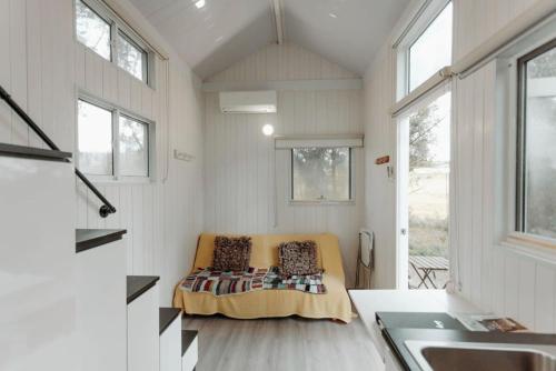 a room with a couch in a tiny house at Raintree Farmstay by Tiny Away in Sarsfield