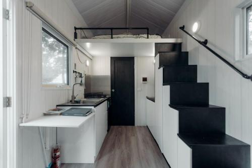 a small kitchen with a staircase in a tiny house at Raintree Farmstay by Tiny Away in Sarsfield