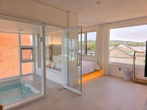 a bathroom with a glass shower and a swimming pool at 대천 아이오션 풀빌라 호텔 in Koryŏng