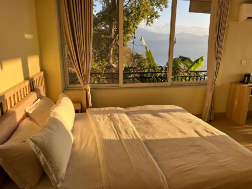 a bedroom with a bed and a large window at Superview Lodge - Family-Run, Himalayan Sunrise in Pokhara