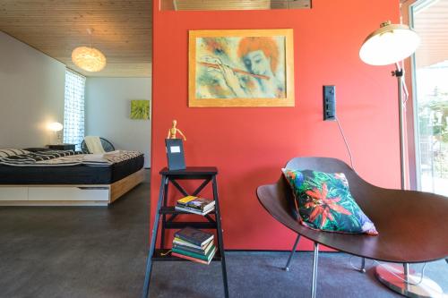 Cette chambre est dotée d'un mur rouge avec une chaise et un lit. dans l'établissement Il Cubo, à Berne