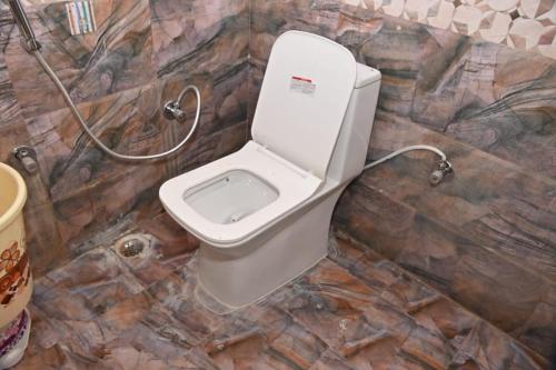 a bathroom with a toilet in a stone wall at pitambara studio apartment with kitchen in Karadoho