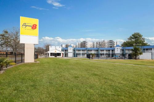 a building with a sign in front of a grass field at Super 8 by Wyndham Portsmouth - Norfolk in Portsmouth