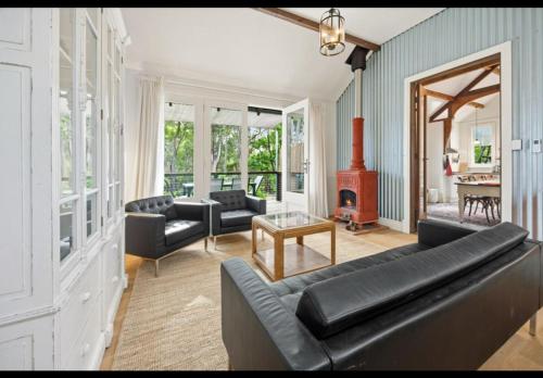 a living room with a black couch and a fireplace at Amara Creek Retreat in Margaret River Town