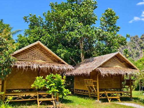 two huts with straw umbrellas on the grass at Tarzan Bamboo hut in Khao Sok National Park