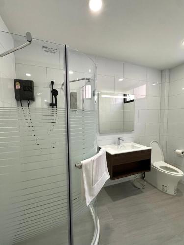 a bathroom with a shower and a sink and a toilet at Whiteinn - ไวท์อินน์ in Nonthaburi