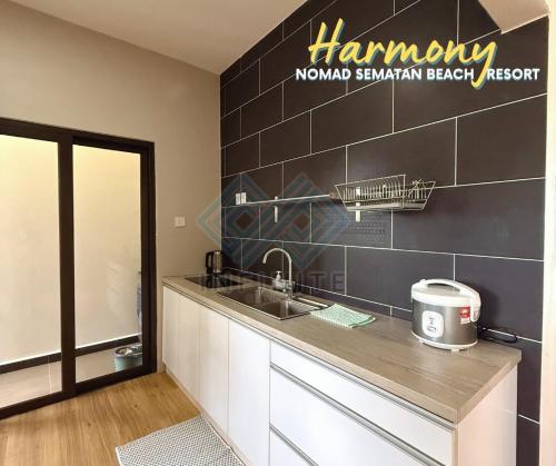 a kitchen with a sink and a sign on the wall at Harmony Serene 3BR Nomad Sematan Beach Resort in Sematan