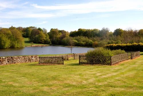 two benches sitting in a field next to a lake at Les Vergnes in Saint-Pardoux-le-Neuf