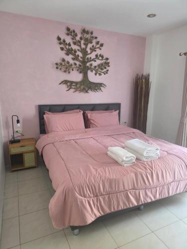 a bedroom with a pink bed with two towels on it at Chokdee rooms kata in Kata Beach