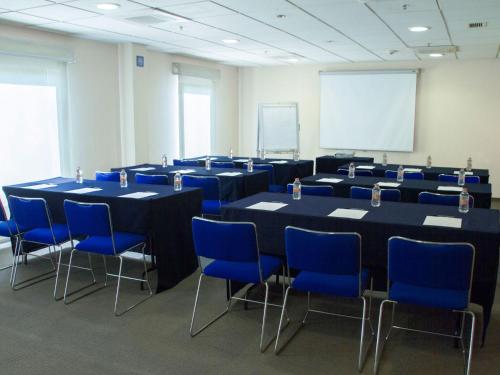 a conference room with tables and blue chairs and a whiteboard at City Express by Marriott Tepotzotlán in Tepotzotlán