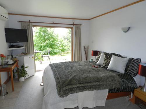 a bedroom with a bed with a blanket on it at Puketotara Lodge in Kerikeri