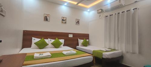 a bedroom with two beds with green and white pillows at Hotel Royal Green Inn in Chennai